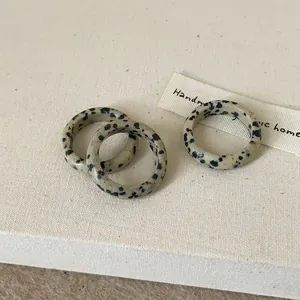 Macro detail of three minimalist speckled natural stone rings on textured linen surface