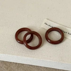 Close-up of three minimalist reddish-brown agate stone rings on a linen background