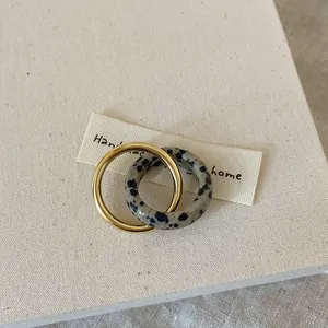 Macro shot of interlocking gold metal ring and spotted natural stone on canvas background