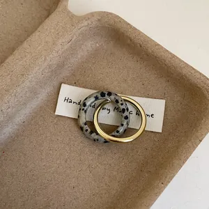 Detail of interlocking dalmatian stone and gold metal band rings for women