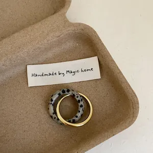 Detail view of double-layer interlocking gold metal and dalmatian stone rings