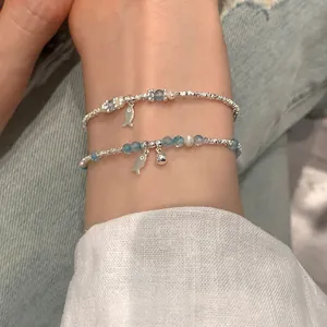 Blue crystal fish bracelet with silver beads and pearl accents on female wrist