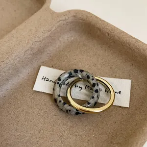 Minimalist double-layer interlocking ring set featuring gold metal and dalmatian stone