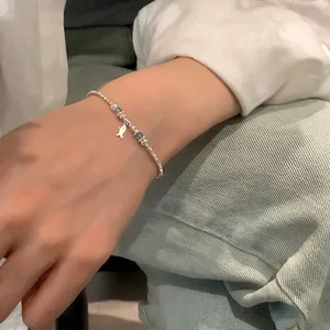 Detailed view of a silver bead bracelet with blue crystal accents and fish charm