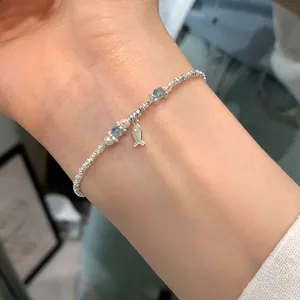Silver bracelet with blue crystal beads, small fish pendant and white pearls on wrist