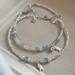 Macro detail of silver fish bracelet with blue crystal beads and elegant pearls