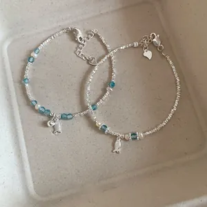 Macro detail of silver fish bracelet with blue crystals and S925 engraved heart tag