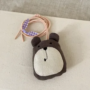 Détail d'un pendentif ours marron fait main en coton et lin avec un petit nœud