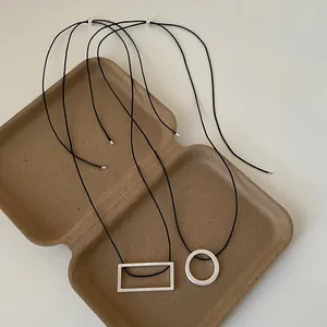 Macro shot of geometric brushed metal pendants on black cords with adjustable beads