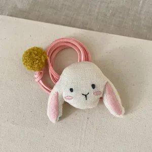 Détail d'un pendentif lapin en tissu avec cordon en daim rose et pompon jaune