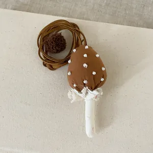 Détail du pendentif champignon en tissu avec perles blanches, dentelle et pompon