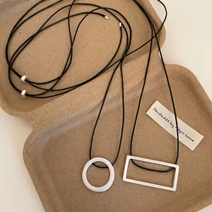 Detail of minimalist matte silver geometric pendants on adjustable black cord necklaces