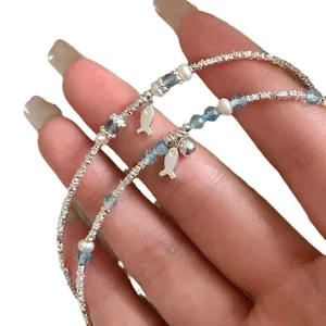 Blue crystal and silver fish charm bracelet featuring delicate white pearls and bells