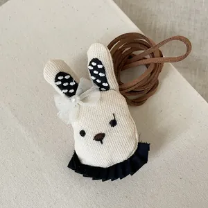 Détail de pendentif lapin en tissu avec nœud en dentelle, perle et cordon en daim