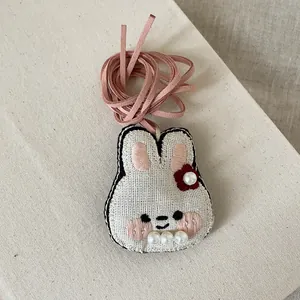 Vue détaillée du pendentif lapin en tissu fait main avec broderie et perles douces