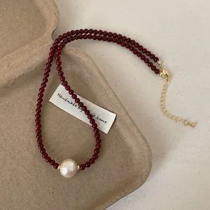 Elegant dark red beaded necklace featuring a large cream cotton pearl and gold clasp