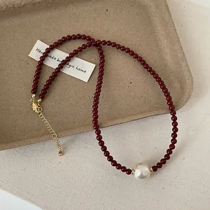 Detail of red beaded necklace with large baroque pearl and gold plated lobster clasp