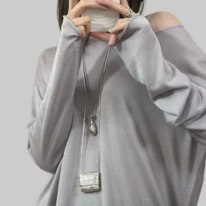 Détail d'un collier à pendentif sac tressé argenté superposé avec une goutte et une bague