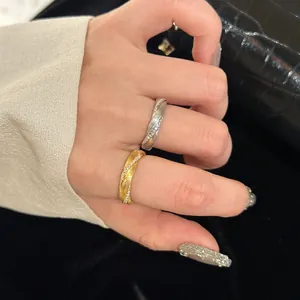 Detailed macro view of twisted rope rings with brushed metal and zircon inlays on hand