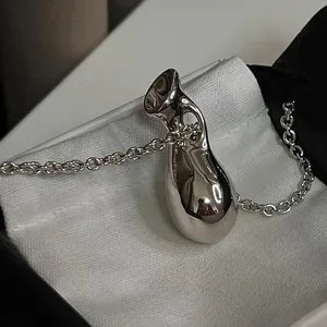 Vue macro d'un pendentif bouteille abstrait en argent poli avec une chaîne à maillons fins