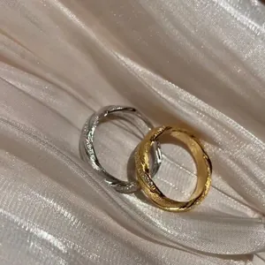 Macro detail of twisted textured rings with sparkling stones on soft silk fabric
