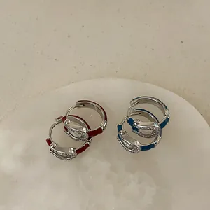 Detail of silver horseshoe earrings with red and blue enamel and zircon inlay