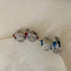 Detail of red and blue horseshoe earrings with micro-pave cubic zirconia on stone tray