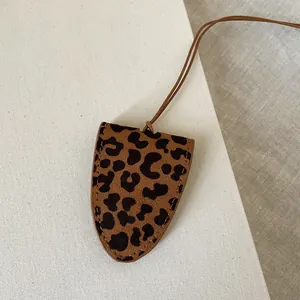 Macro detail of leopard print leather sunglasses holder with brown lanyard and neat stitching