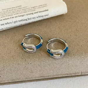 Detail of horseshoe-shaped earrings with blue enamel and pavé zircons on paper background