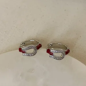 Detail view of horseshoe earrings with micro-set zircon and red enamel finish