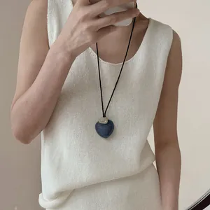 Detalle de un colgante de mezclilla con forma de corazón en un collar de cordón negro