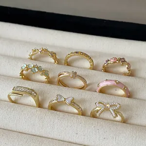 Selection of gold floral and butterfly enamel open rings on a cream display box