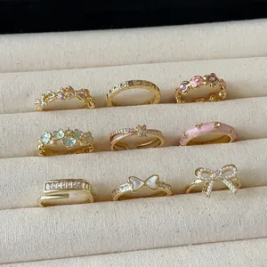 Nine-piece gold-tone floral ring set with pink enamel butterflies and daisy designs