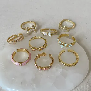 Set of 9 vintage gold-finished adjustable rings with enamel flowers and faux pearls