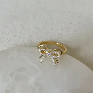 Macro detail of golden butterfly ring with white pearls and central square zircon