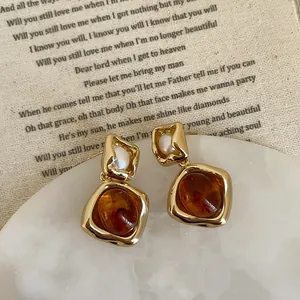 Close-up of vintage amber resin earrings with white pearl and gold-tone metal frame