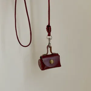 Gros plan d'une mini pochette en cuir rouge foncé avec fermoir rétro et cordon tressé