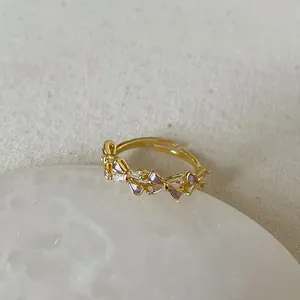 Macro detail of golden open ring featuring purple enamel butterfly and zircon inlays