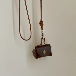 Détail d'une pochette rétro en cuir marron foncé avec bouton pression et cordon tressé