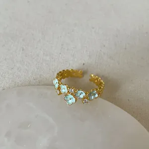 Detail of light blue enamel flowers and sparkling zircons on an adjustable gold-plated ring
