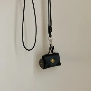 Gros plan du mini sac pendentif en cuir noir avec bouton pression et cordon de cou