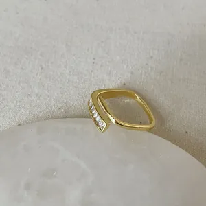 Close-up of golden geometric open ring with rectangular zircon stones on stone base