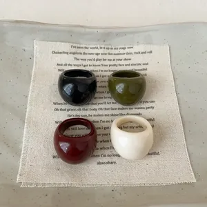 Four-piece set of wide resin rings in black, olive green, burgundy, and cream white colors