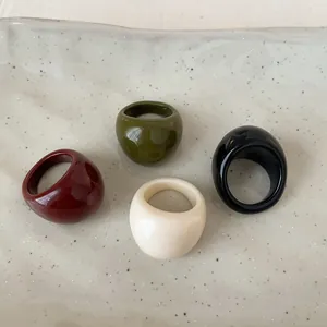 Minimalist oval resin rings set in dark red, olive green, cream white, and glossy black