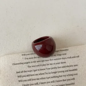 Close-up of a glossy burgundy resin ring with a thick curved design on vintage paper