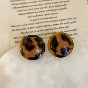 Close-up of vintage leopard print resin earrings on a white marble display tray