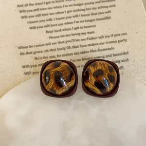 Macro shot of retro leopard print resin stud earrings on vintage paper background