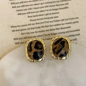 Detail of leopard print resin earrings with vintage golden twisted rope borders