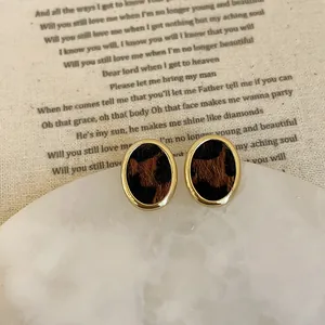 Detailed macro view of vintage leopard resin earrings with a polished gold metal frame