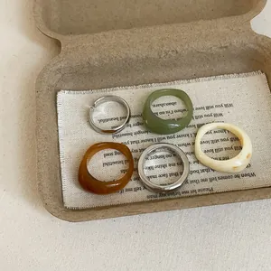 5-piece geometric resin and silver metal ring set in green, amber, and cream white colors